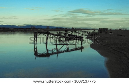 Old fishing pier, clouds, mountains, river, field, shore and colorful sunset. Silence and immense beauty. Country Romance