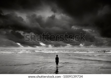 alone boy near the beach with dramatic stormy sky   during monsoon season  Royalty-Free Stock Photo #1009139734