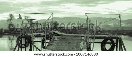 River and the old wooden fishing pier on the background of a magical sunset and mountains. Rural landscape