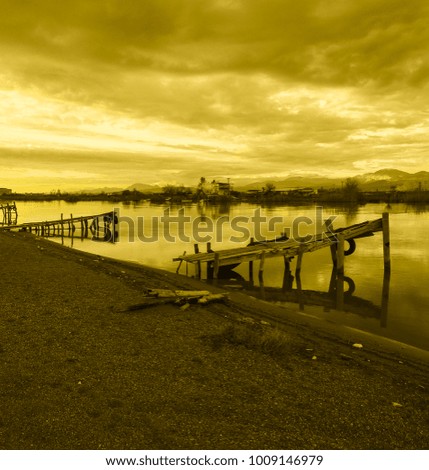 Old fishing pier, clouds, mountains, river, field, shore and colorful sunset. Silence and immense beauty. Country Romance
