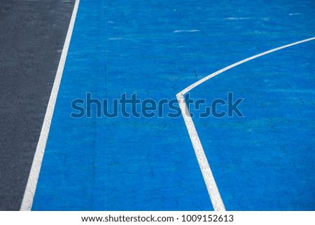 Abstract, blue background of newly made outdoor basketball court in park. Visible asphalt texture, freshly painted lines. 