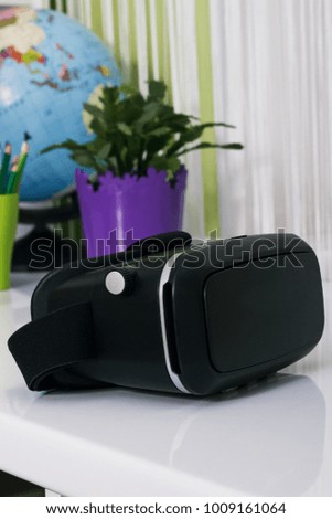 Virtual reality glasses on the table, indoors. Digital virtual reality device. Soft focus background