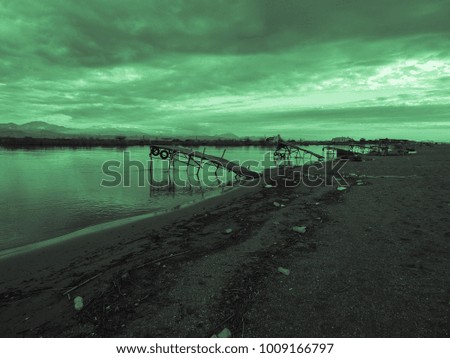Green sunset and old fishing wooden pier and river on a background of mountains. Meditative relaxing natural landscape