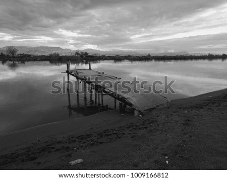 Old fishing wooden pier and river on a background of mountains and colorful sunset. Meditative relaxing natural landscape