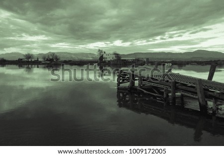 River and the old wooden fishing pier on the background of a magical sunset and mountains. Rural landscape