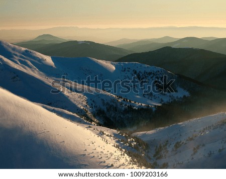 Sunset on the top of a snowy winter mountains on sky background