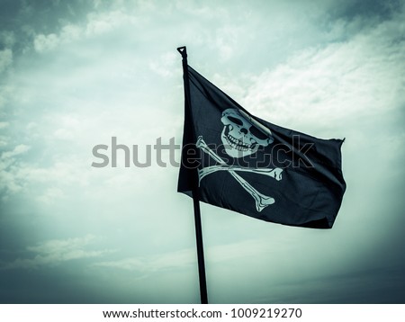 photo shows a pirate flag depicting a skull-and-crossbones with stormy cloudy sky at the background