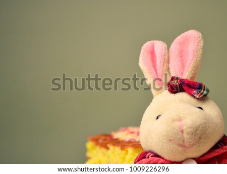 Ears and muzzle of the Easter bunny. On the background a plate with cakes and a green wall.