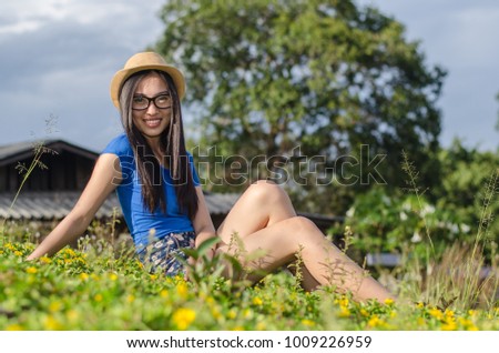 Happy Asians female in cowgirl hat and wear glasses,Sitting on meadow and looking at camera with toothy smile