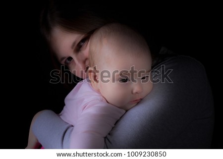 Little Caucasian Baby Girl Protected In Mothers Arms - Beautiful Studio Soft Shot On A Dark Background