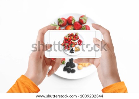 Girl taking picture of different kind of berries on plate
