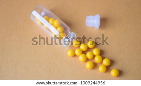 Ascorbic acid is scattered out of the jar on an orange background