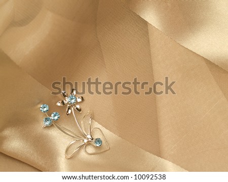 silver broach on silky background pearly folded