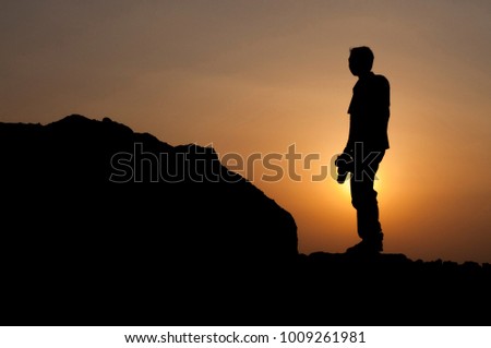 Silhouette of a photographer standing on a rock at a beach with beautiful scenery of the sunsets