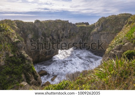 Natural swimming pool pond ocean aerial view with wave breaking sea water on rocky shore rough seas with turquoise water gradient and foam on background,  Pancake rocks Punakaiki  Pass Southern Island