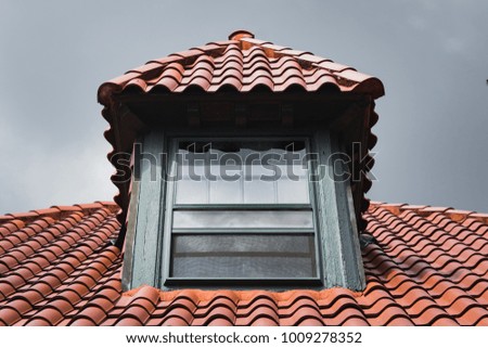 A window and red tile roof. 