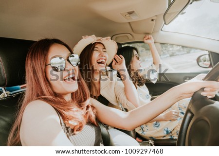 Group of happy Asian girl best friends laughing and smiling in car during a road trip to vacation. Royalty-Free Stock Photo #1009297468