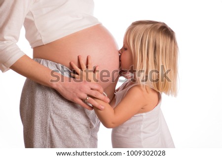 Little girl embracing  pregnant mother and kissing her belly