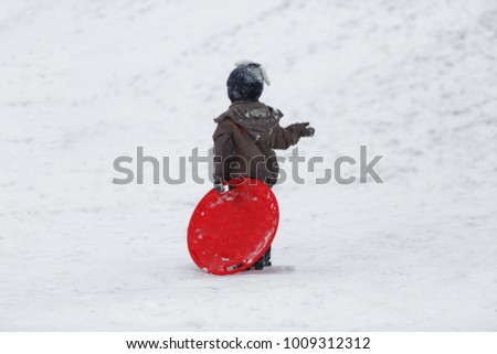 handsome boy has fun on his winter holidays. Makes snowman, sledding 