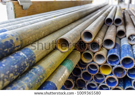 Mental scaffolding pipe stack together on scaffolding plank wood shelve with blue, green and yellow mark at the tip for build the temporary structure. Royalty-Free Stock Photo #1009365580