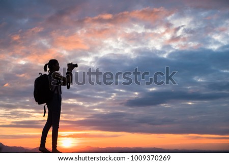 Professional woman photographer taking camera outdoor at sunset