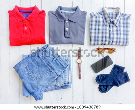 Men's clothes and accessories. Jeans, glasses, sock, smartphone on wooden background. Top view with copy space