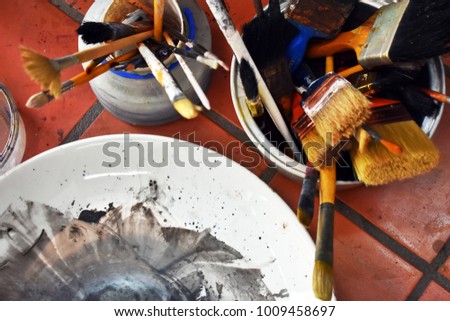 Top view group of equipment about painting, color plate, many size of paint brush in pot, brick floor background, creative arts theme, creativity concept 
