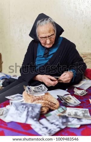 Senior woman looking at old photos indoor