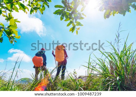 Travel background. Two backpacker standing on top of mountain looking forward to blue sky in sunny day. Freedom lifestyle. Fresh nature. Picture for add text message. Backdrop for design art work.