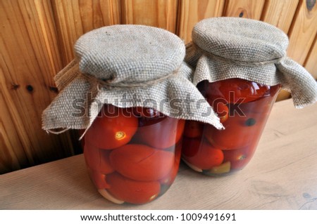 a group of cans with canned tomatoes and cucumbers, burlap on the lid and twine