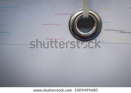 Metal ring or grommet on a vinyl banner, secured with a zip tie. Riveted steel eyelet used for hanging banners, detail with a zip tie.