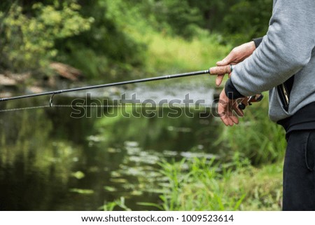 Fisherman`s hand holding fishing rod with reel. Close up.