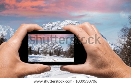 Man and woman hand capturing Alpin Winter landscape with smartphone