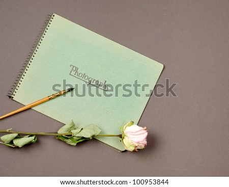 Vintage photo album with dried pink rose and antique fountain pen.