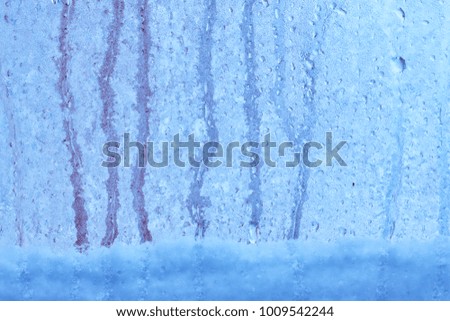 Closeup shot of a steam window with water drops, overcast gray day. Blurred background with blue color shades