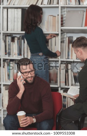 handsome student talking by smartphone in library