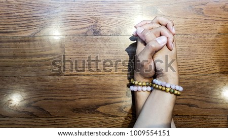 Lover hold each other hand on the wooden table. Their hands have been worn with the same bracelets.