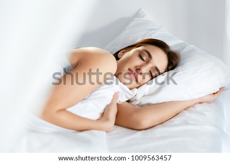 Sleep. Young Woman Sleeping In Bed. Portrait Of Beautiful Female Resting On Comfortable Bed With Pillows In White Bedding In Light Bedroom In Morning. People Sleep. High Quality Image. Royalty-Free Stock Photo #1009563457