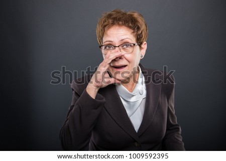 Business senior lady making yelling gesture with one hand on black background