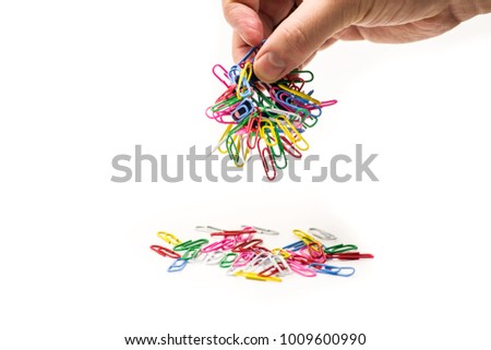 man hand holding magnet attracting metal paper clips