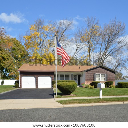 Brown Suburban Ranch home with two car garage blacktop driveway blue sky clouds USA Royalty-Free Stock Photo #1009603108