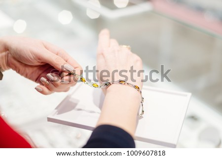 Woman owner of jewelry shop presenting silver bracelet with amber. Customer service in jewelry store. Royalty-Free Stock Photo #1009607818
