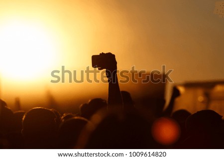 Silhouette of smartphone in a hand over crowd