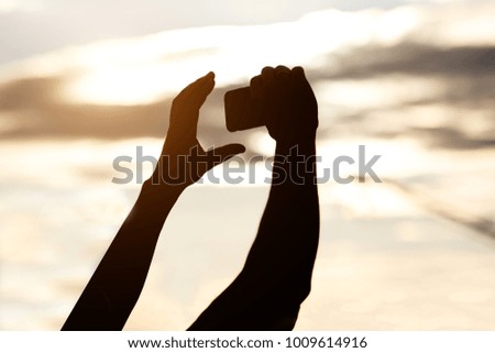 silhouette of man hands holding mobile phone at sunset