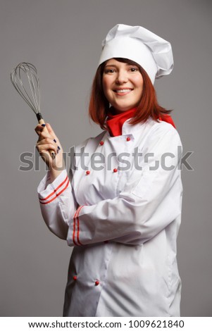 Image of woman cook in white robe and cap with whisk in hand
