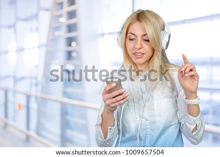 Happy young blonde woman listening to music