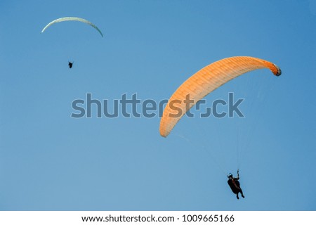 Two paragliders flying on the background of blue sky. Paragliding in the sky on a sunny day.