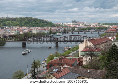 View from one of Prague's cultural centers called Vyšehrad on the river Vltava with its bridges and the ships floating on it. In the distance is Prague Castle and a hill with a lookout tower.