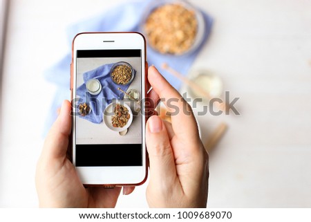 Young woman food blogger takes photo for blog, pic of bowl with Greek yogurt homemade granola, mixed nuts, almond, cashew, hazelnut. Healthy vegetarian protein diet breakfast. Selective focus, closeup