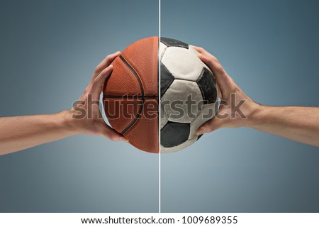 Hands holding soccer and basketball balls on gray studio background. concept of confrontation, differences in taste and preference